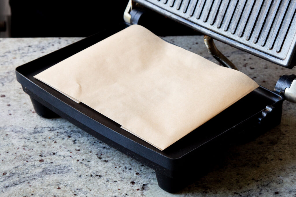 panini press lined with folded up parchment paper