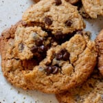 close-up of peanut butter cookies with chocolate chips on a plate, cookie is broken apart, so you can see the inside