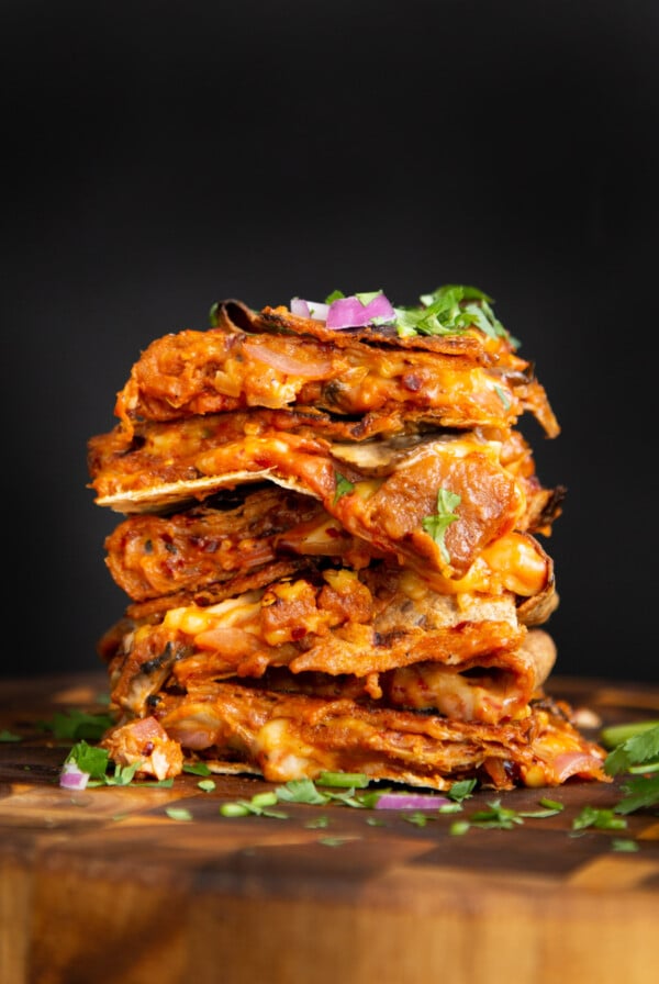 stack of vegan pizza quesadilla slices on a wooden cutting board