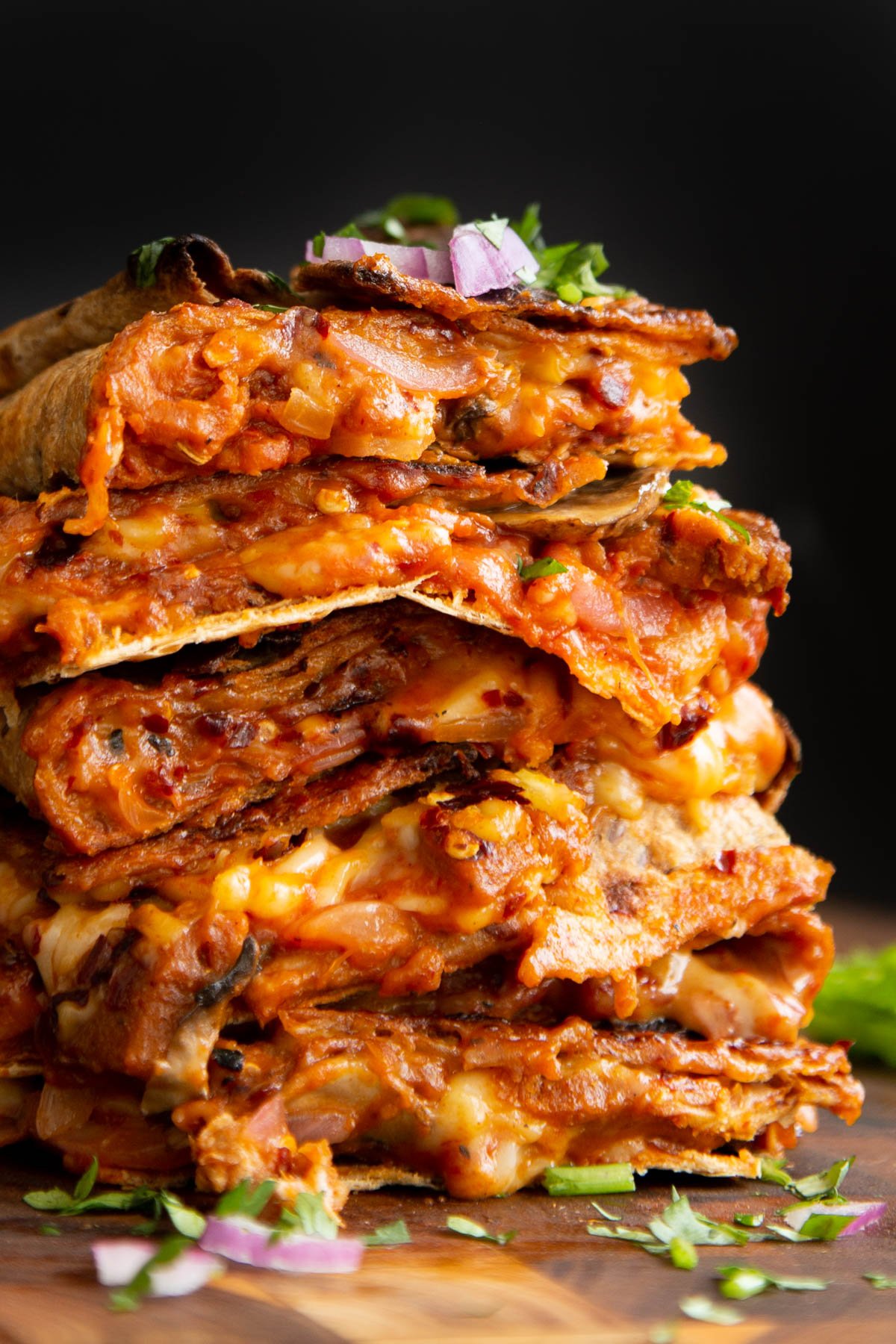 stack of vegan pizza quesadilla slices on a wooden cutting board