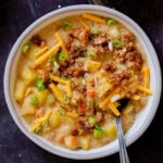 bowl of smoky vegan potato soup topped with tofu crumbles, green onions, and vegan cheese