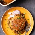 overhead view of a serving of keema lentil casserole on a plate with sliced onion