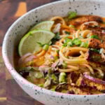 close-up of a bowl of butter ramen with tofu and a lime wedge