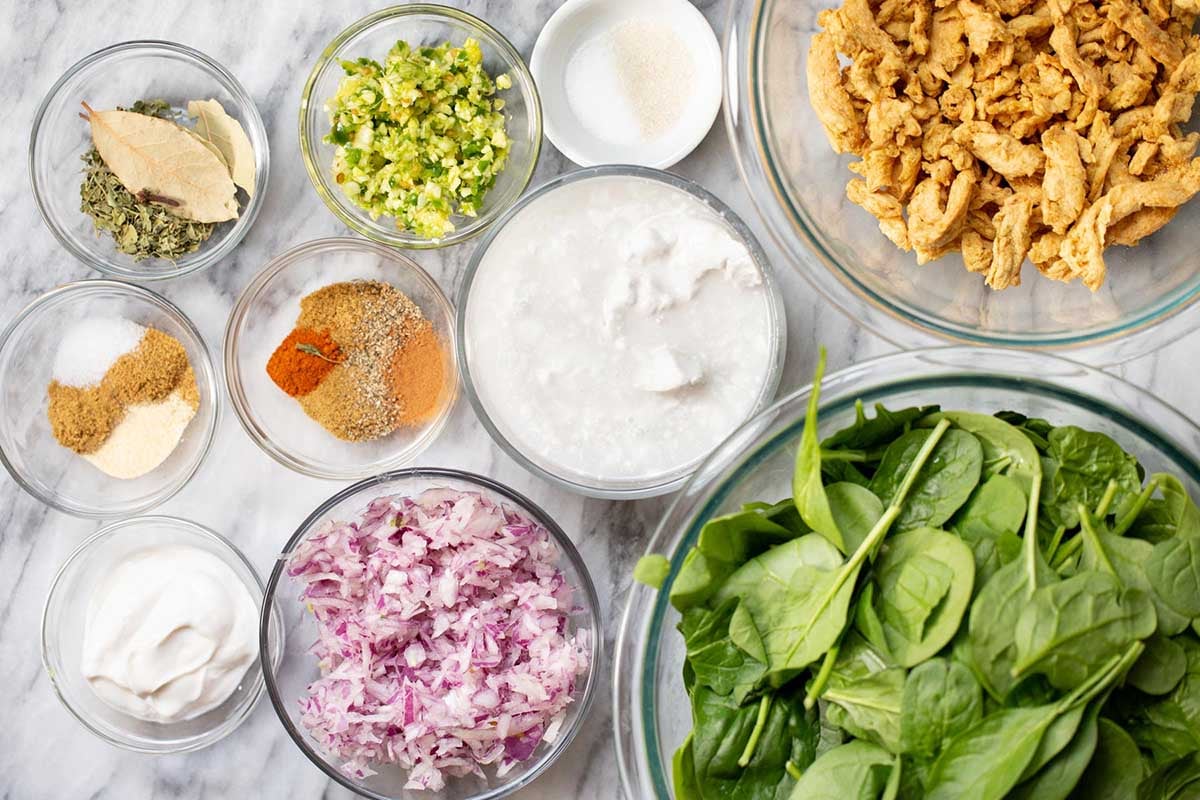spinach curry ingredients in bowls on a kitchen counter