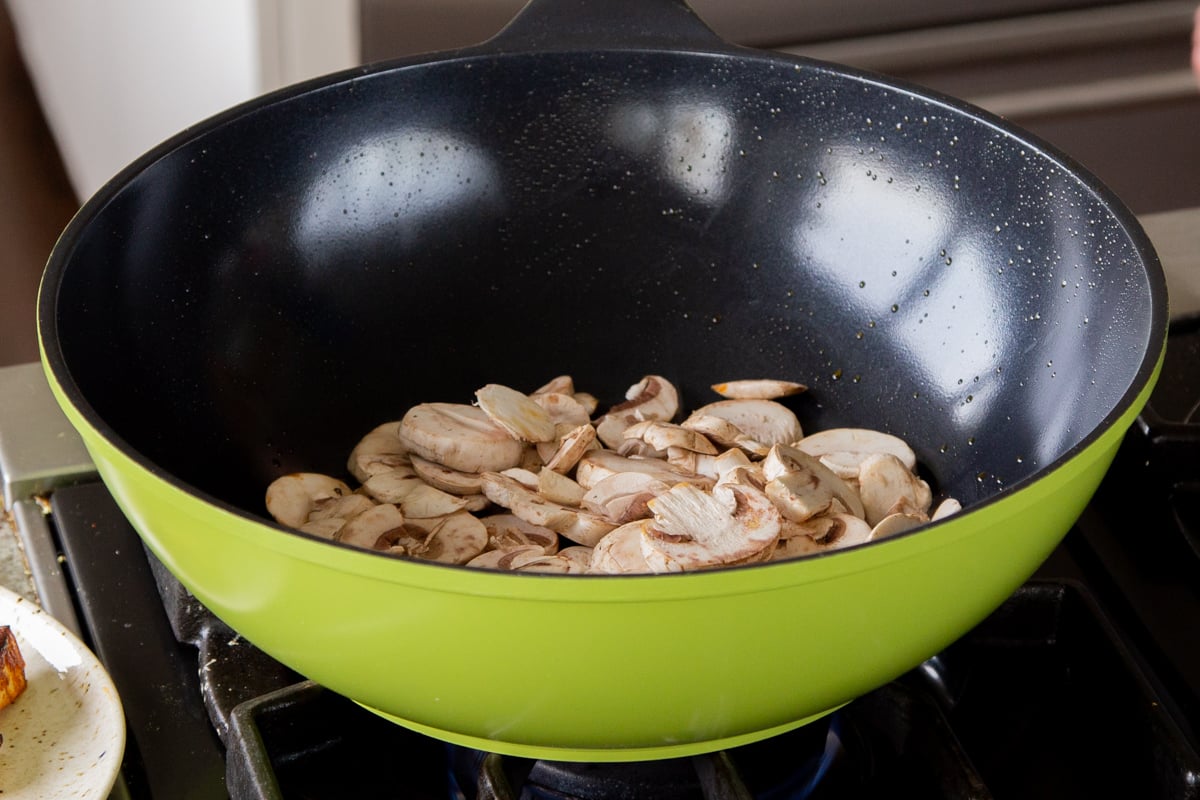 adding mushrooms to the pan after removing the tofu