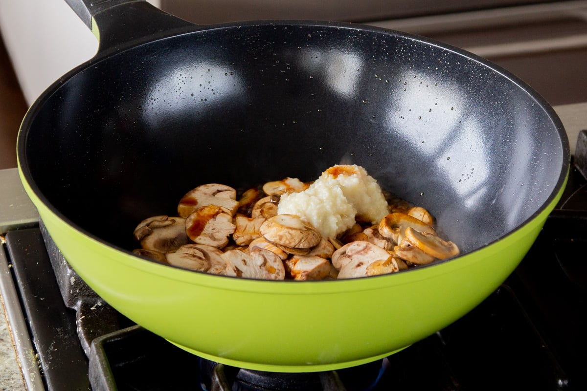 adding ginger-garlic paste to the pan of mushrooms