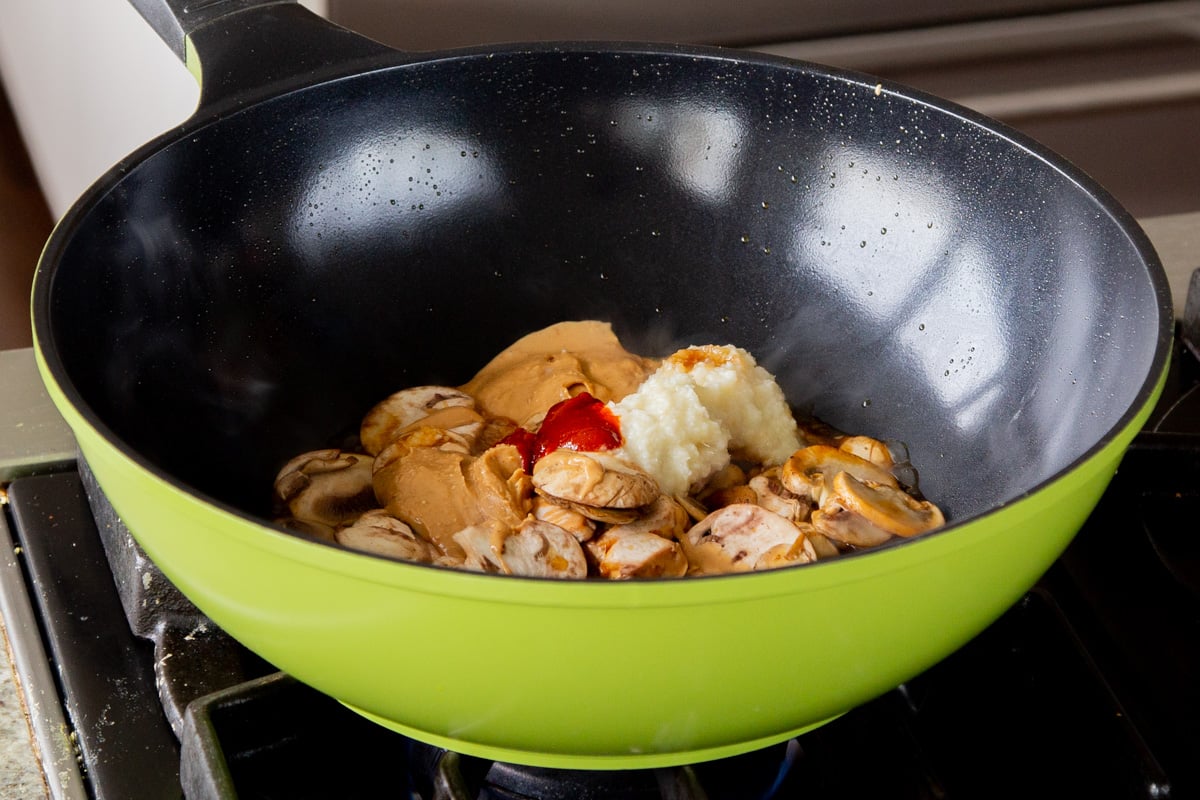 adding peanut butter and spicy gochujang to the pan of mushrooms