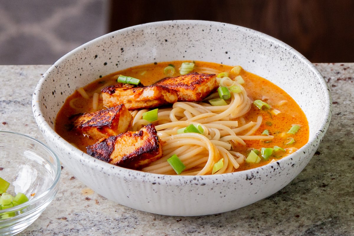 spicy peanut butter ramen in the bowl, after adding tofu and green onions