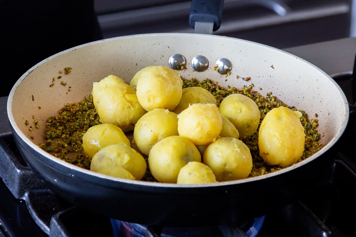 adding cooked, peeled potatoes to the pan of peanut-sesame seed-spice mixture