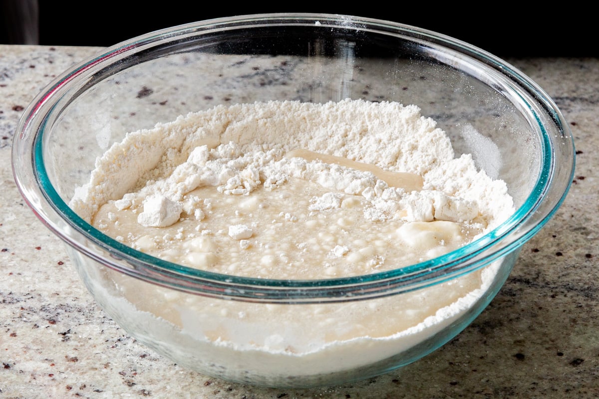 flour and other dry ingredients floating on top of the wet ingredients in the bowl