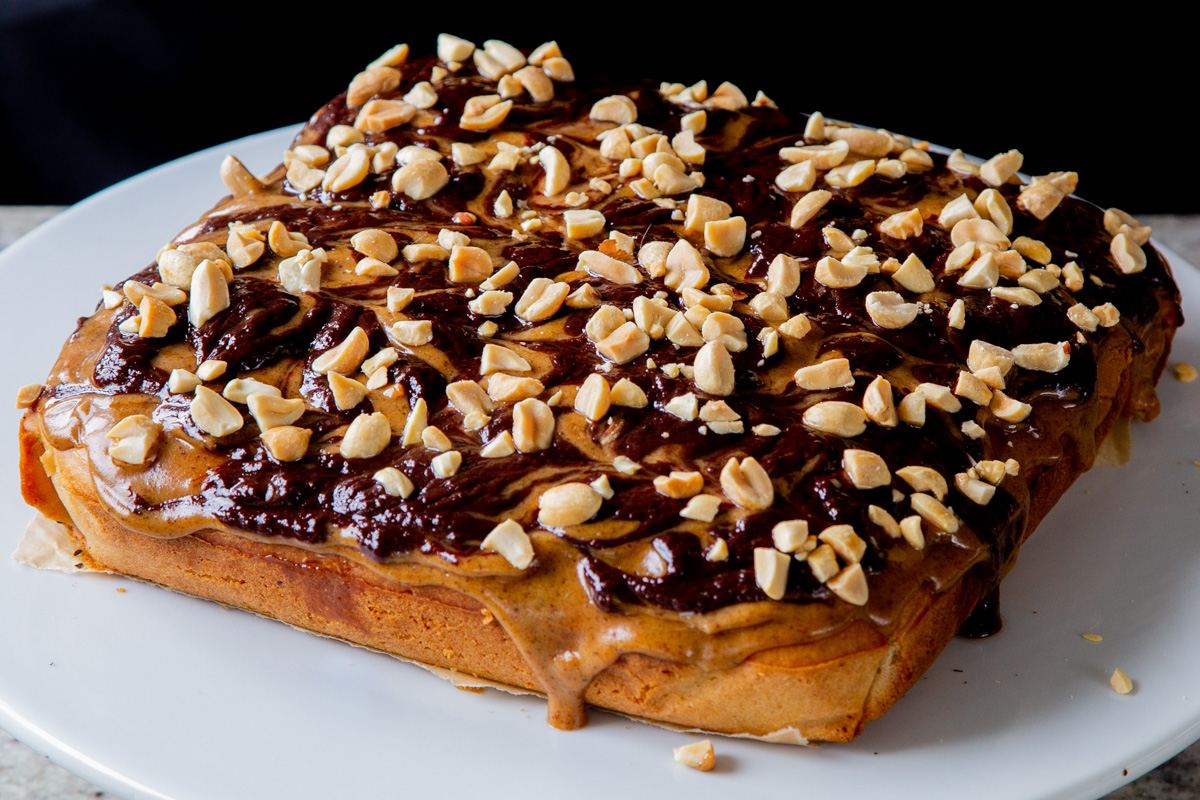 Snickers cake topped with peanuts, before slicing