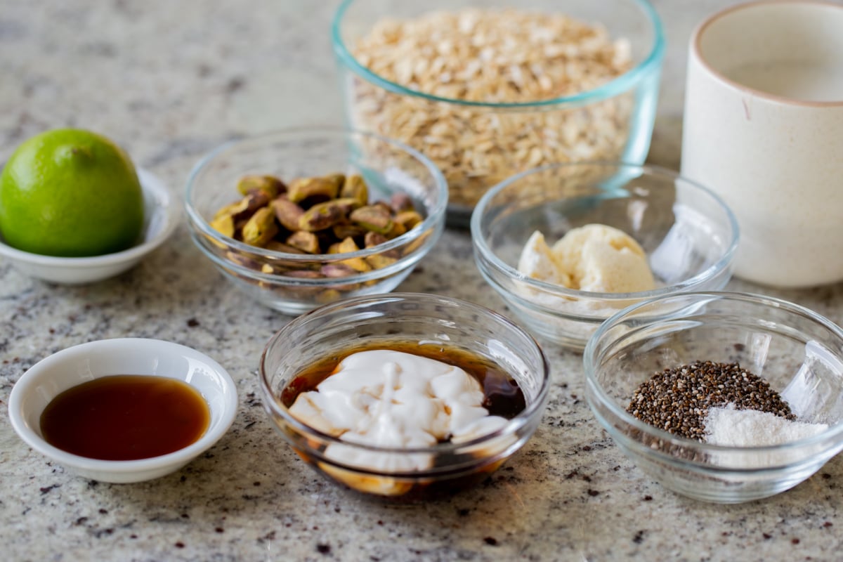 rolled oats, nuts, and seasonings in bowls on a kitchen counter