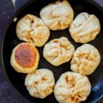 cooked bao in a pan with one flipped over, so you can see the crispy bottom