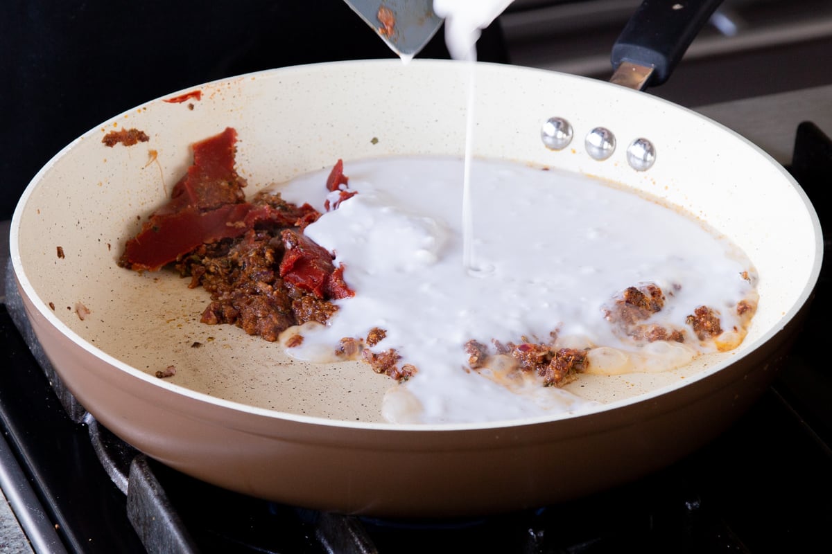 adding coconut milk to the frying pan
