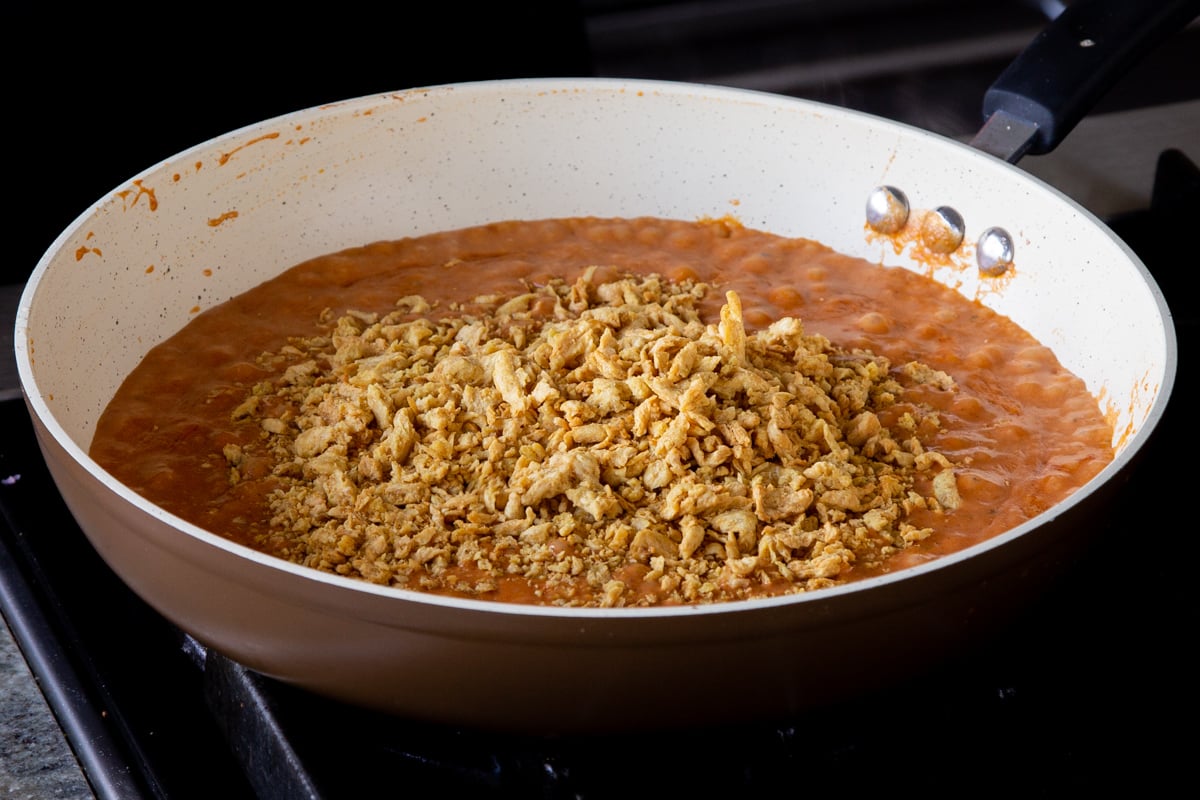 adding soy curls to the pan of vegan butter chicken sauce