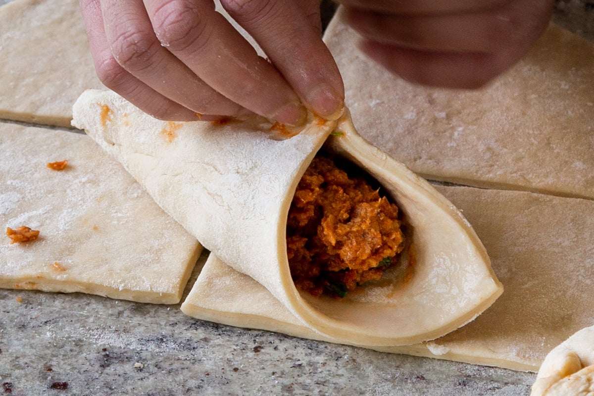 pinching the first 2 corners of the dough together