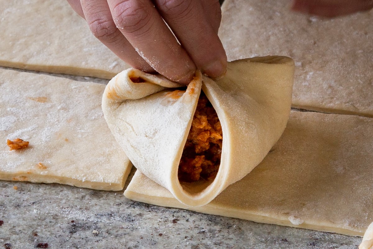 pinching the opposite 2 corners of the dough together