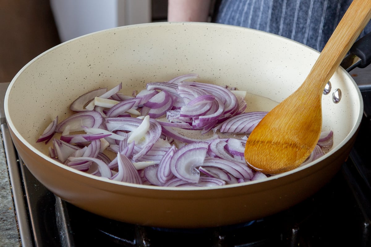 adding sliced red onion to the frying pan