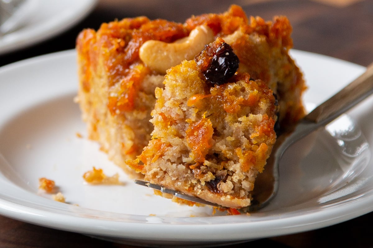 slice of carrot halwa cake on a white plate, with a bite taken out