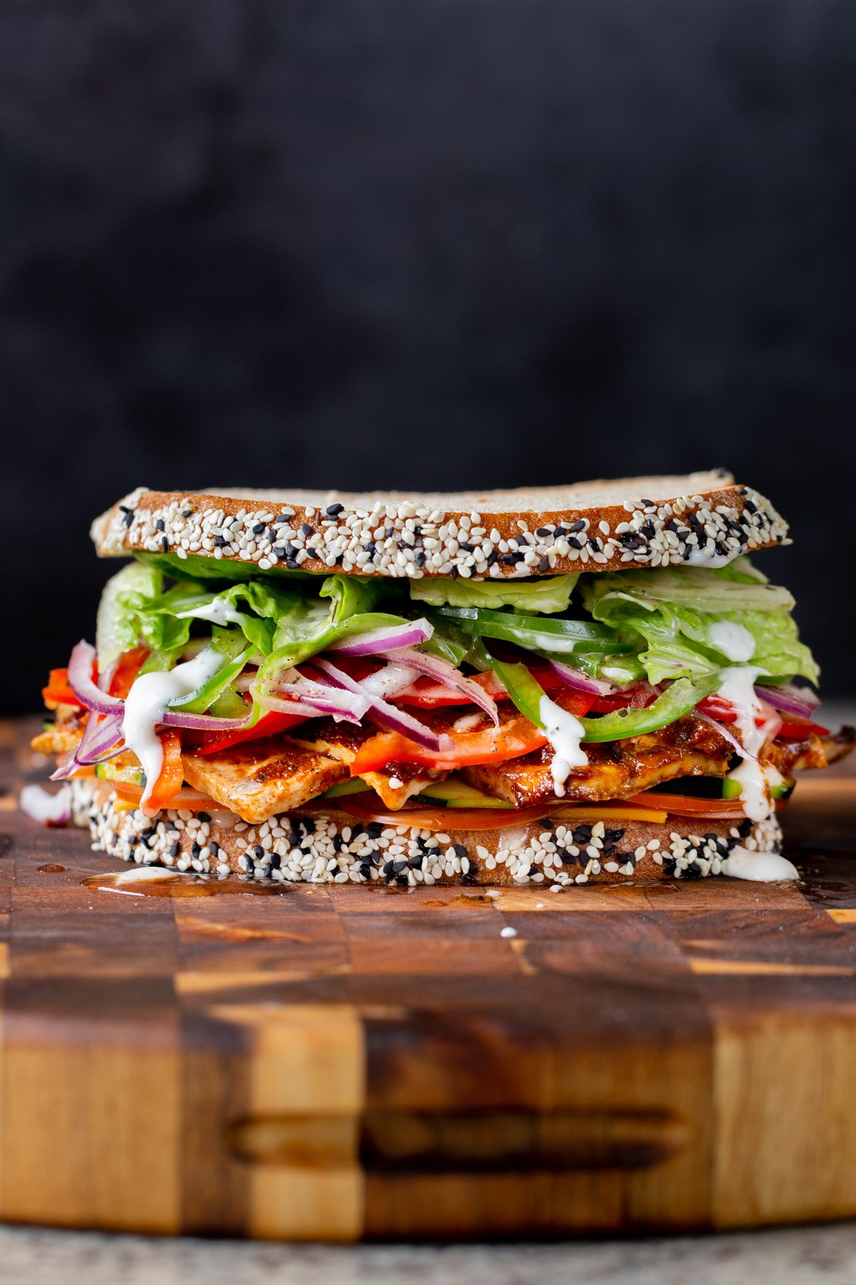 vegan club sandwich with veggies and tofu deli meat on a wooden cutting board