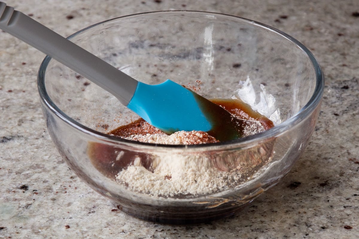 adding wet marinade ingredients to the bowl of salt and spices