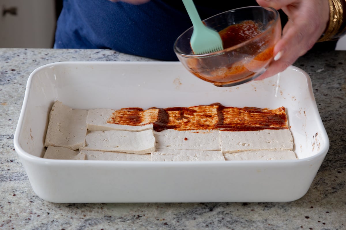 brushing the marinade onto the tofu deli slices in the pan before baking