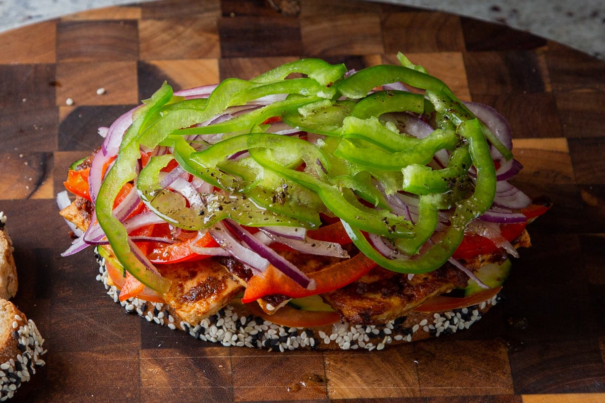 layering green bell pepper slices onto the sandwich