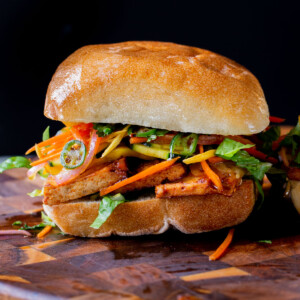 gochujang tofu banh mi with pickled veggies on a wooden cutting board