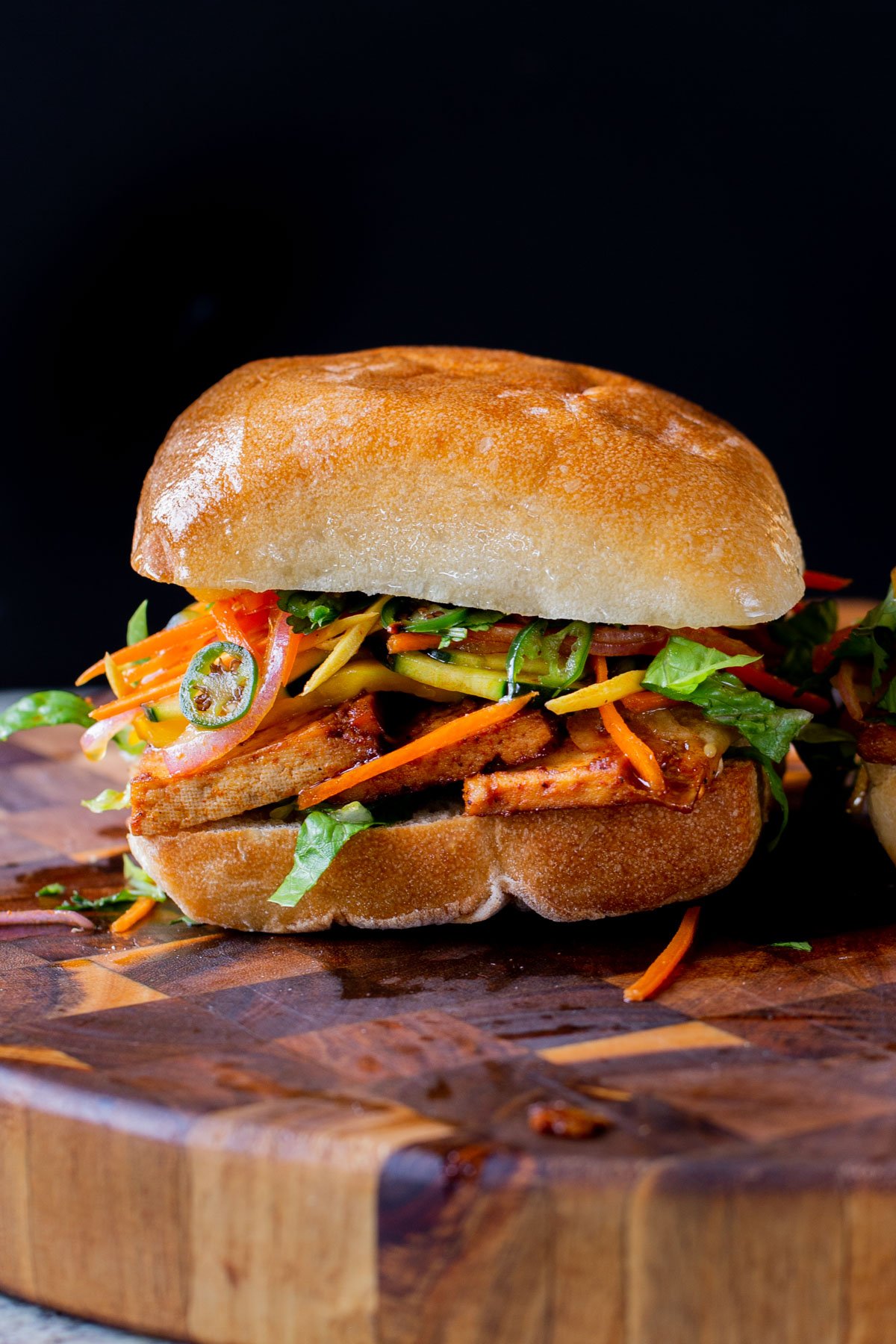 gochujang tofu banh mi with pickled veggies on a wooden cutting board