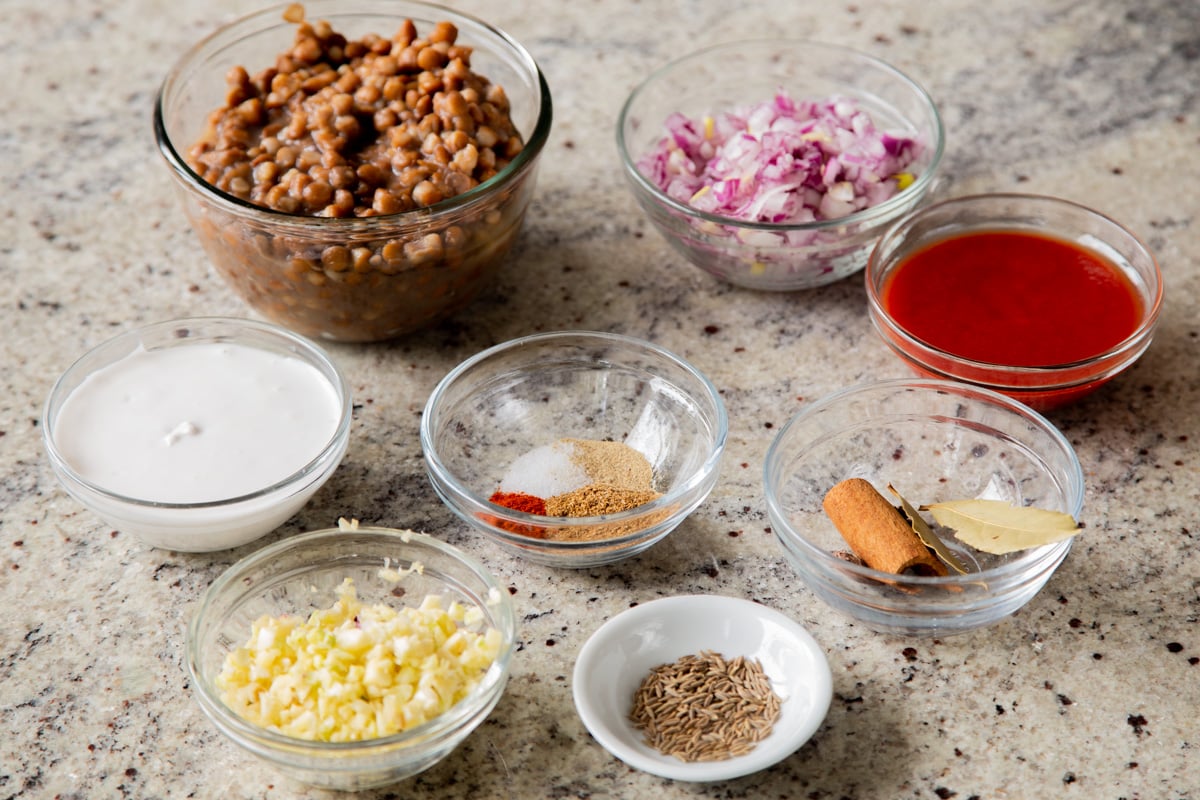 lentils, onion, garlic, and seasonings in bowls on a kitchen counter