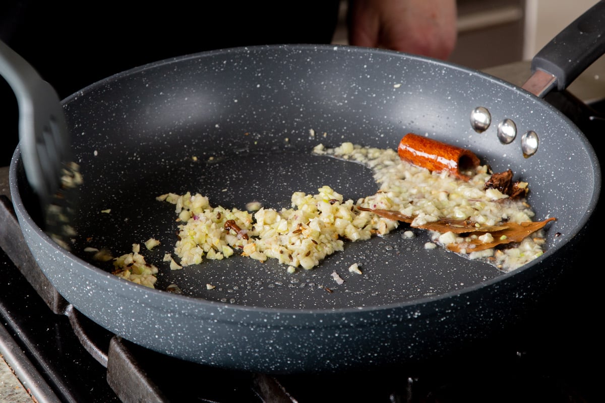 adding garlic to the pan of toasted whole spices
