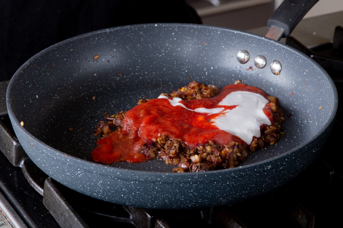 adding tomato paste and non-dairy yogurt to the pan of aromatics and spices