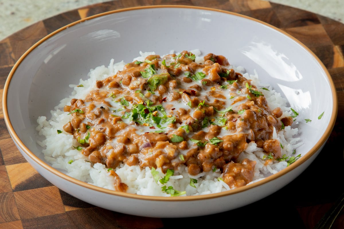 bowl of lasooni dal over rice with cilantro and a swirl of cream