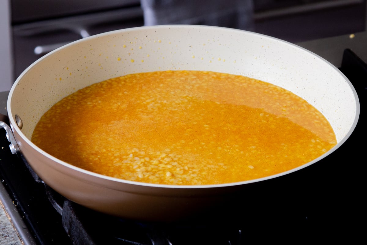 water and spices added to the moong dal in the pan