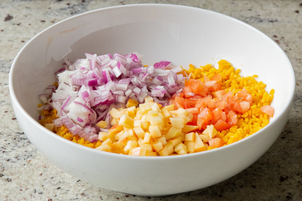 adding apple, onion, and tomato to the bowl