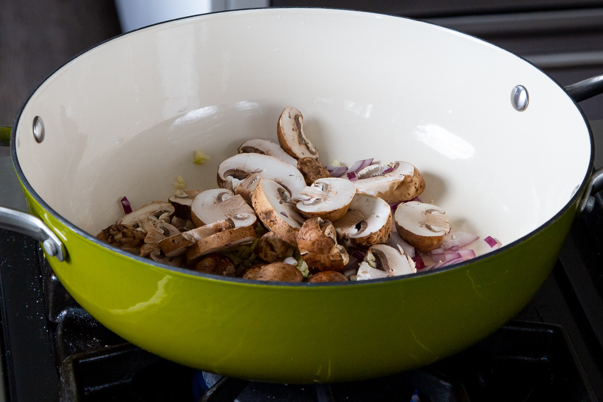 adding the mushrooms to the pan of sautéed onion and garlic