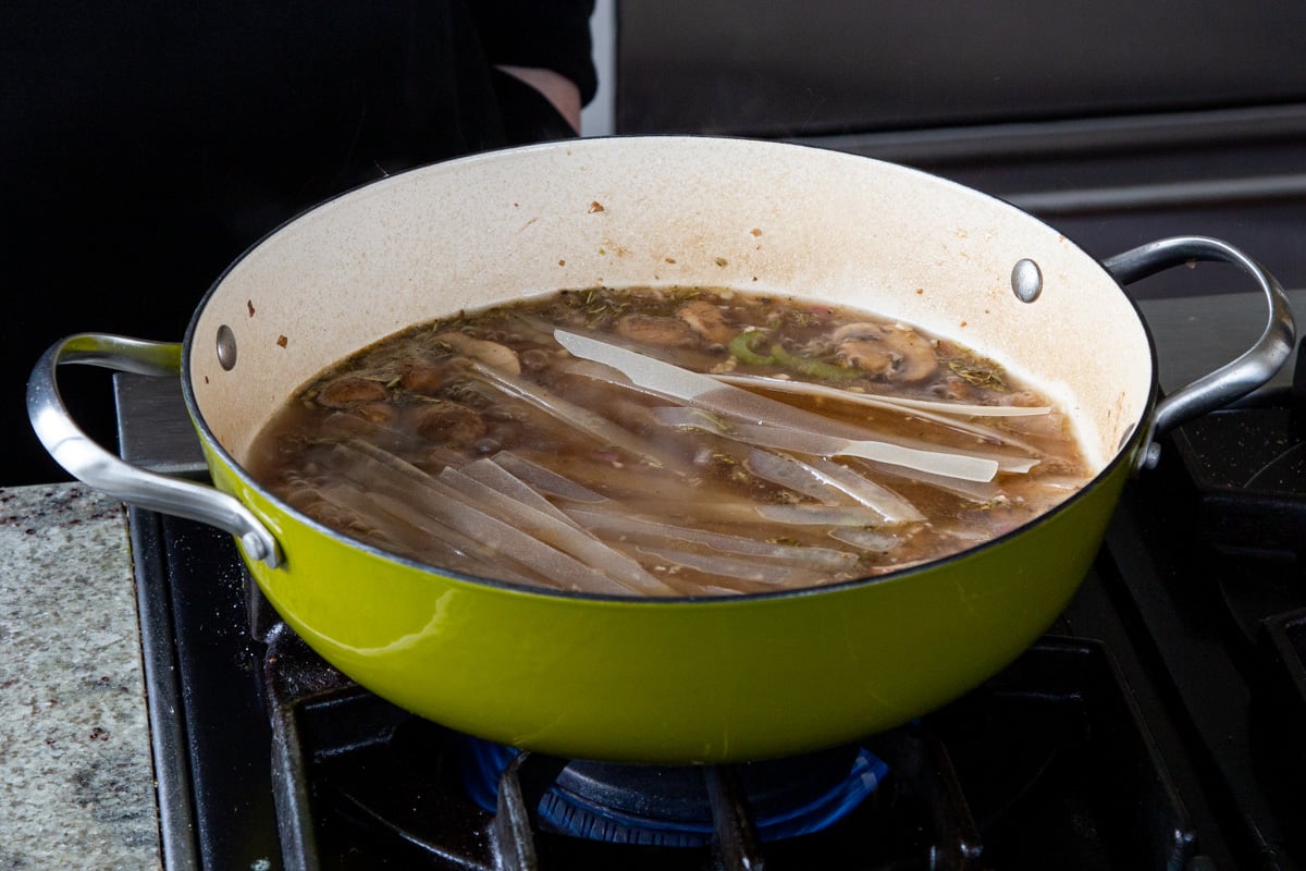 noodles added to the pan of broth and mushrooms