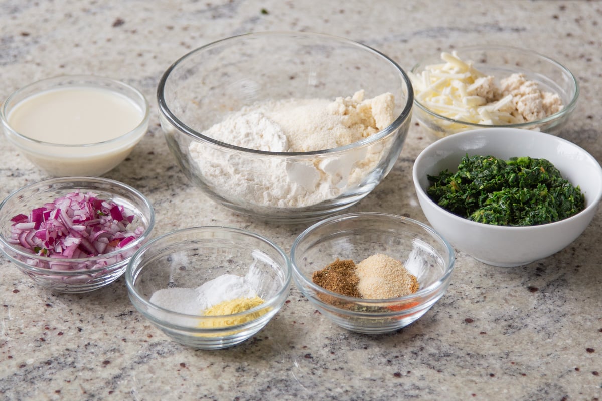 flours, spinach, and seasonings in bowls on a kitchen countertop