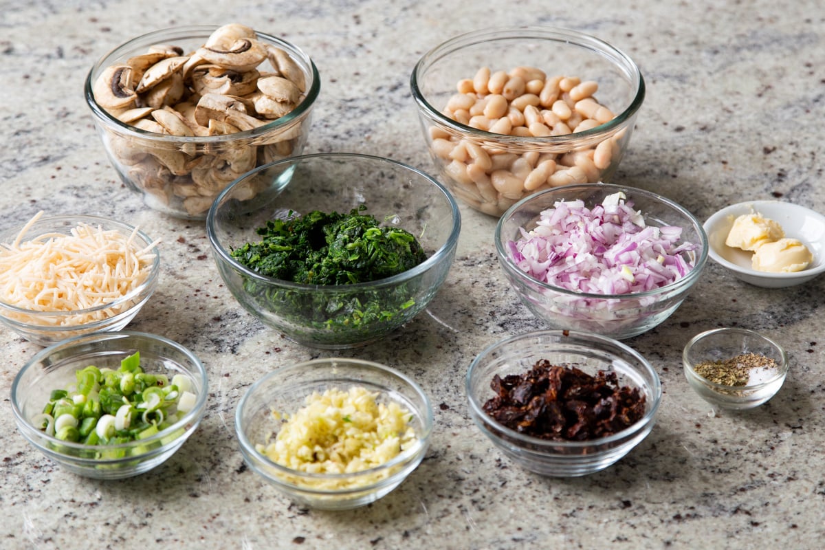 white beans, veggies, and seasonings in bowls on a kitchen counter