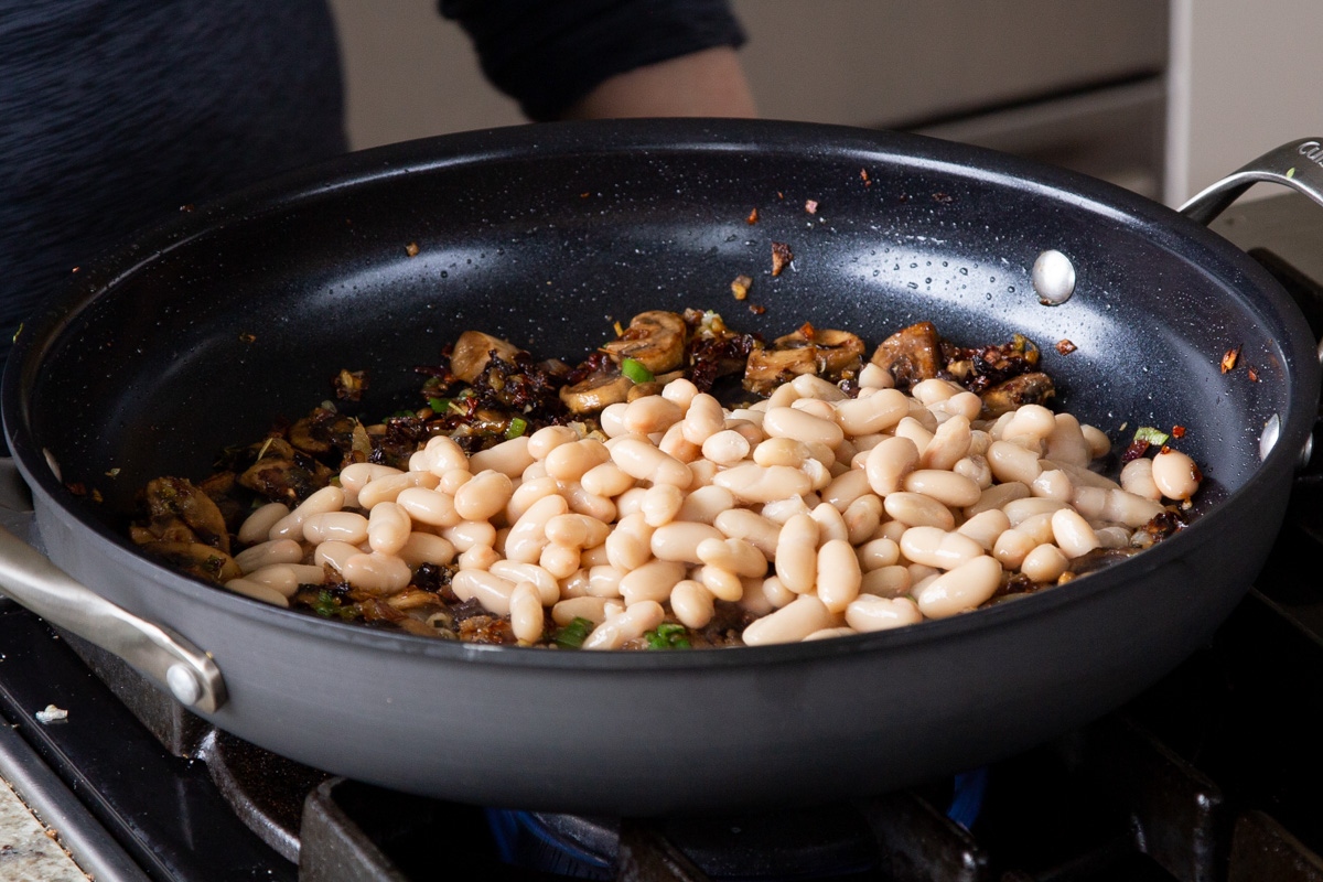 adding white beans to the pan