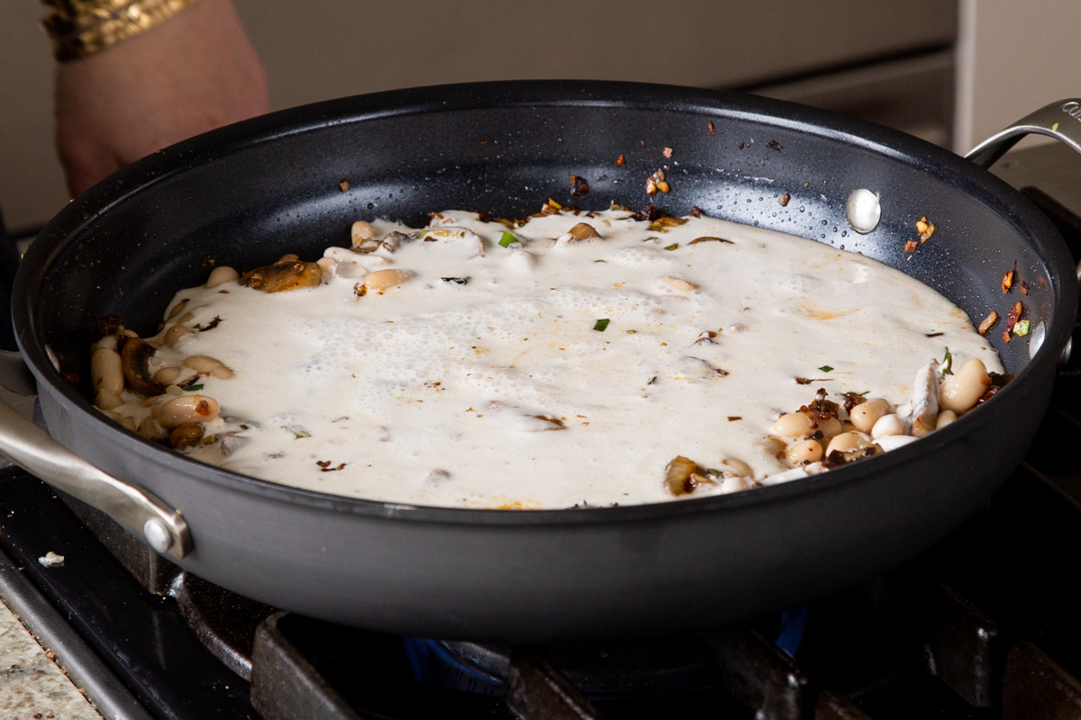 cashew milk added to the pan of beans and veggies