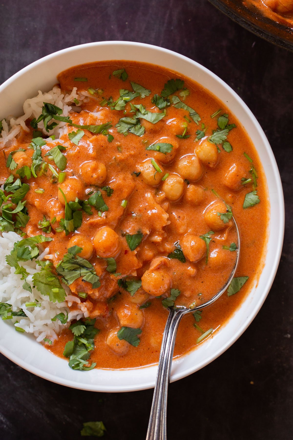 close-up of a bowl of butter chickpeas over rice with cilantro on top