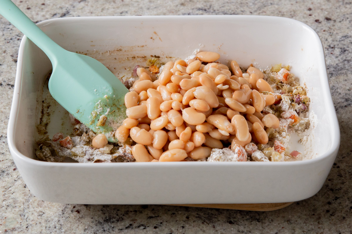 adding beans to the pan of veggies