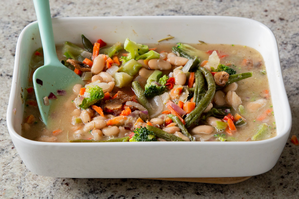adding broth to the baking pan