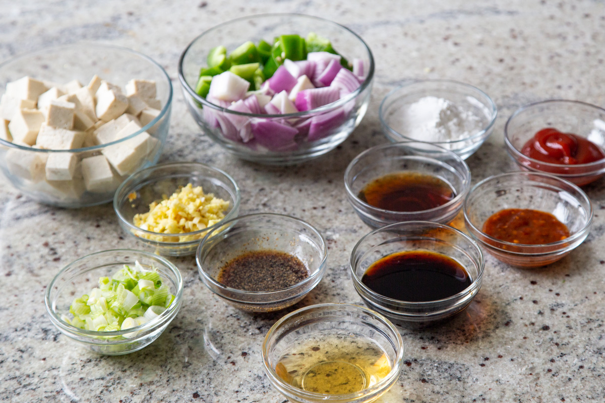 tofu, veggies, sauces, and seasonings in bowls on a kitchen counter