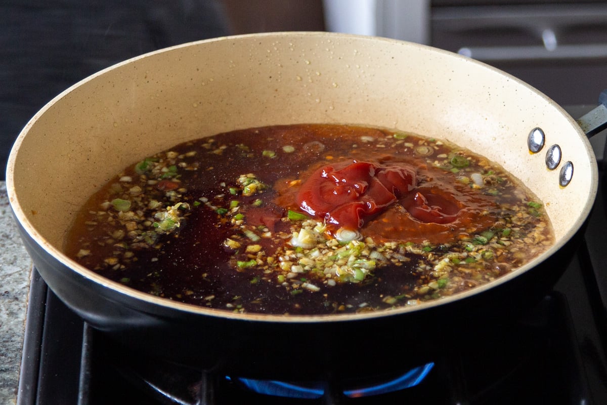 ginger, garlic, and spring onion in the pan, after cooking, with sauces added