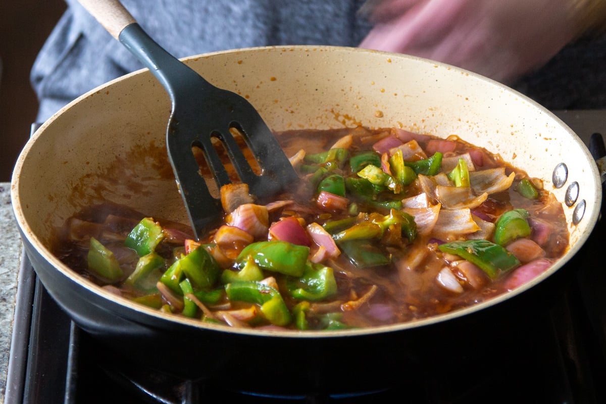 stirring cooked veggies in the pan with a spatula