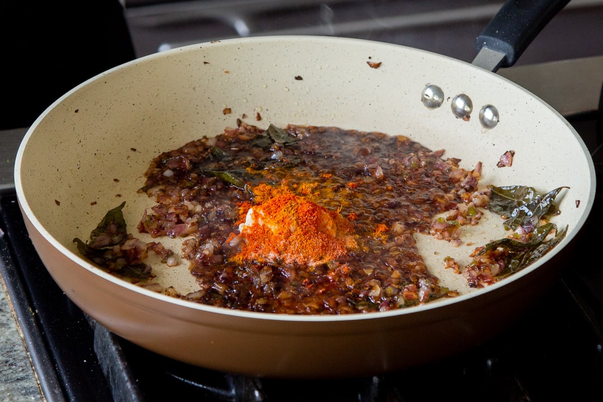 adding dried spices on top of the chili garlic paste in the pan
