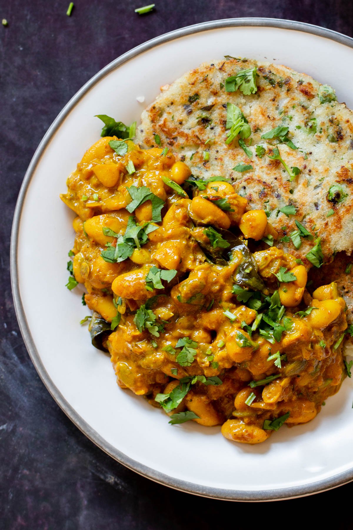 close-up of a plate of spicy white bean stew with cilantro garnish and naan