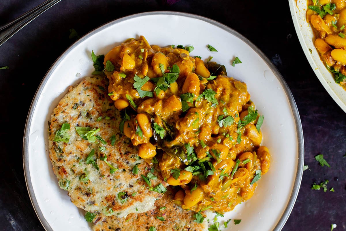plate of spicy white bean stew with cilantro garnish, and naan